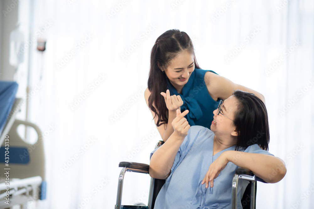an asian old women smlie while sitting on wheelchair at the hospital room with positive thinking, happy patient with young daughter, love from family support during illness concept an asian old women smlie while sitting on wheelchair at the hospital room with positive thinking, happy patient with young daughter, love from family support during illness concept