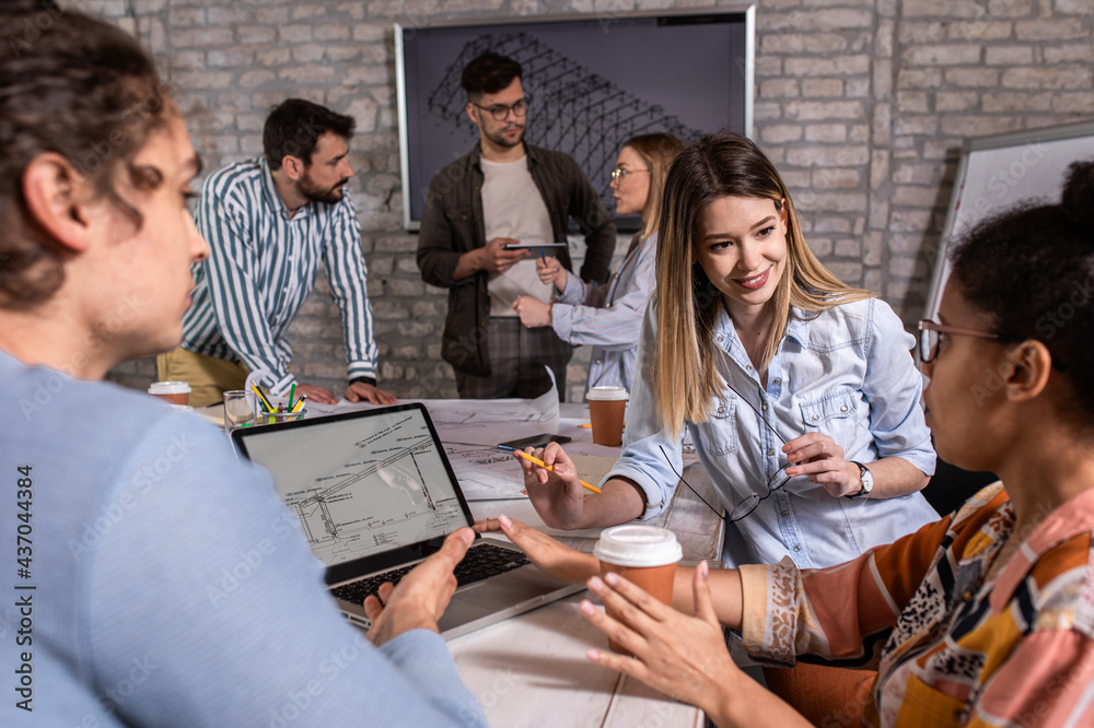 Group of young people discussing architectural designs in the creative office. Group of young people discussing architectural designs in the creative office.