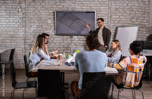 Group of young people discussing architectural designs in the creative office.