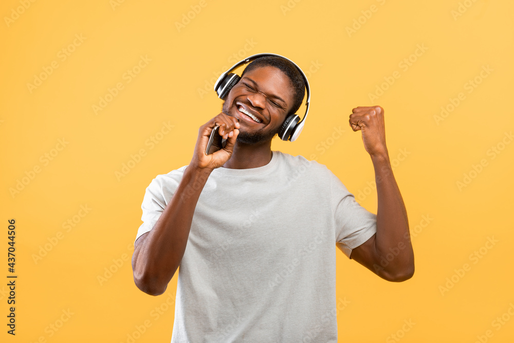 Φωτογραφία Overjoyed african american man in headphones listening to music and singing song