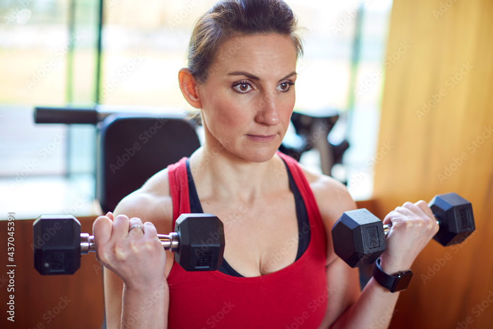 Mature Woman Exercising In Home Gym Lifting Hand Weights Mature Woman Exercising In Home Gym Lifting Hand Weights