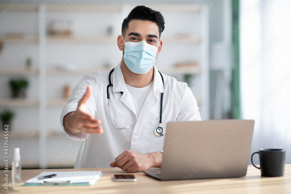 Doctor in face mask working at hospital, greeting patient Doctor in face mask working at hospital, greeting patient
