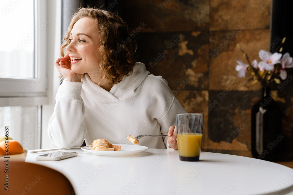 White blonde woman having breakfast while sitting at table in home White blonde woman having breakfast while sitting at table in home