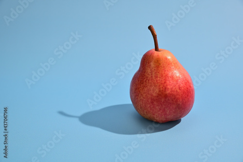 Ripe yellow-red pear with a shank. The pear casts a harsh shadow