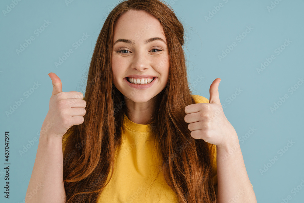 Young ginger woman smiling and showing thumbs up at camera Young ginger woman smiling and showing thumbs up at camera