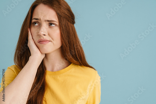Young ginger white woman with toothache looking aside photo