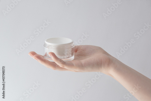 beautiful female hand holding a jar of cream on a white background, cream for skin care, cosmetic rejuvenation procedures.