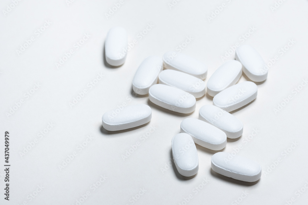 White medicine pills against white background