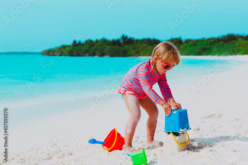 little girl play with sand on tropical beach