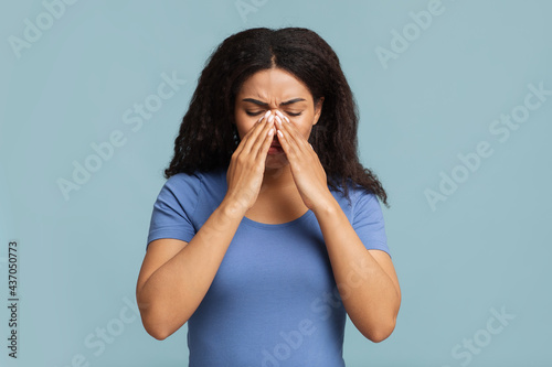 Young black woman touching her nose bridge, suffering from rhinitis, grey background photo