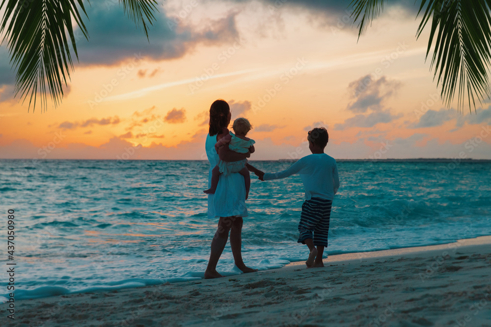 mother and two kids walking at sunset beach mother and two kids walking at sunset beach