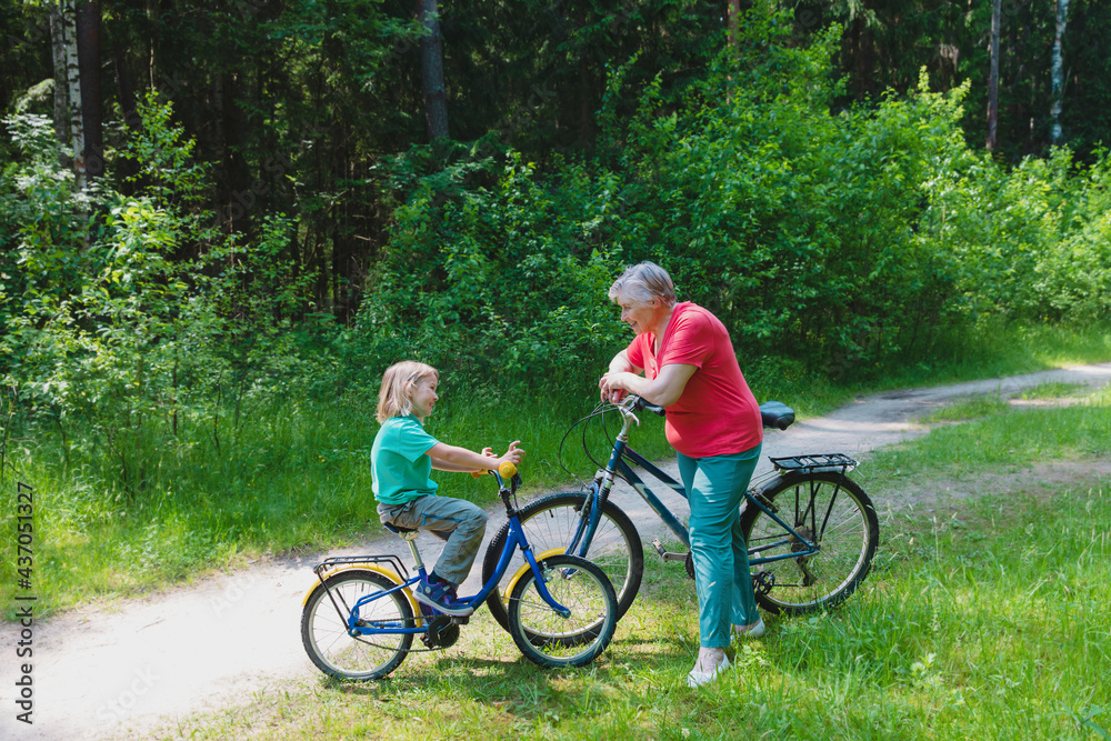 Fototapeta premium happy little girl with grandmother on bike ride in nature