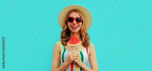 Summer portrait of happy smiling young woman with ice cream shaped slice of watermelon wearing a hat on blue background