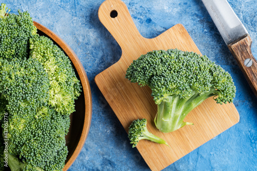 Fresh broccoli with knife on cutting board