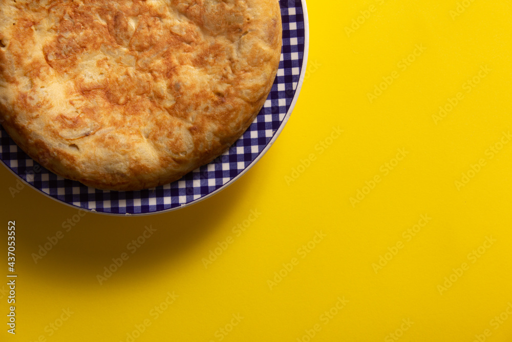 Tortilla de Patatas española. Delicioso plato salado basado en Huevo, Patatas y a veces Cebolla. En fondo amarillo, entera y sin cortar. Tortilla de Patatas española. Delicioso plato salado basado en Huevo, Patatas y a veces Cebolla. En fondo amarillo, entera y sin cortar.