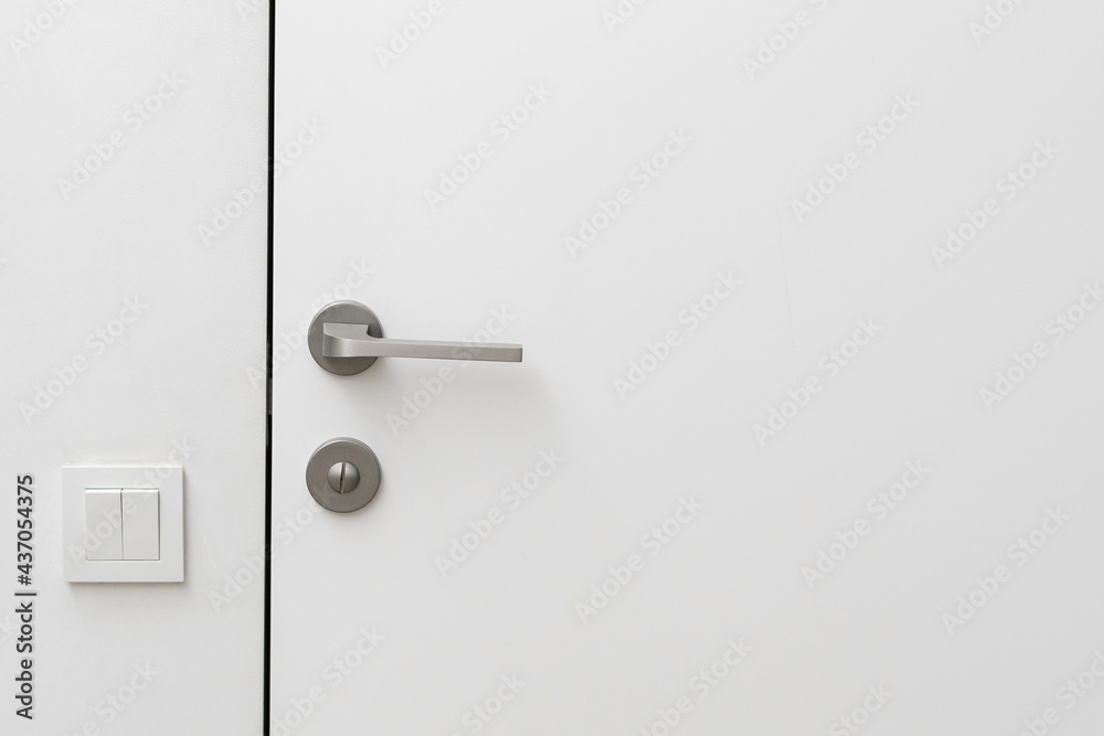 Closed door and light switch on white wall Closed door and light switch on white wall