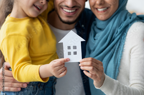 New Home. Happy muslim family holding cutout paper house figure in hands photo