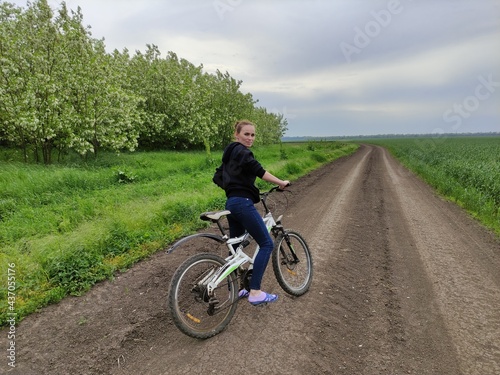 Young woman on bike on the field road looking back