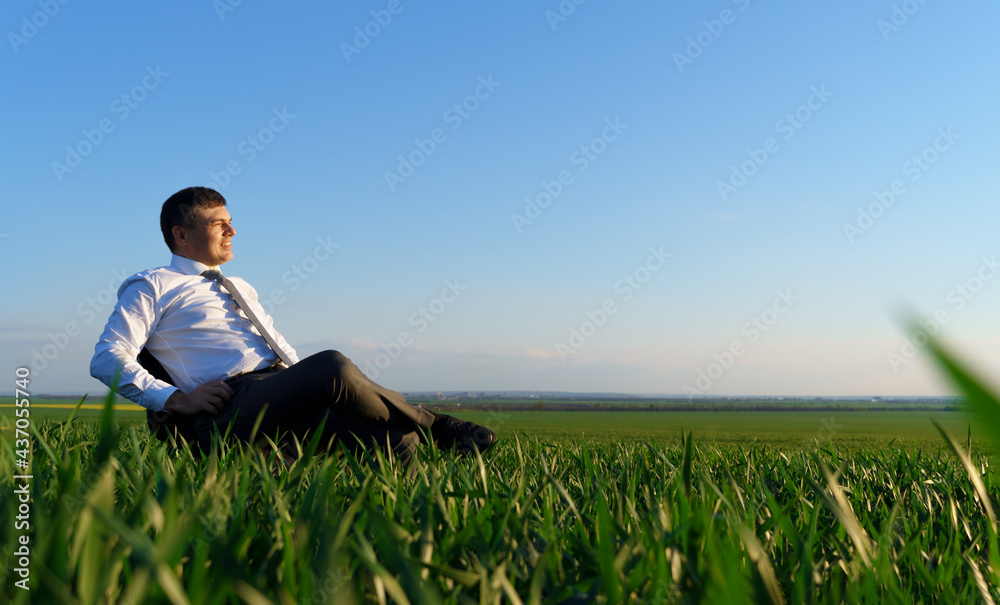 businessman sits in an office chair in a field and rests, freelance and business concept, green grass and blue sky as background businessman sits in an office chair in a field and rests, freelance and business concept, green grass and blue sky as background