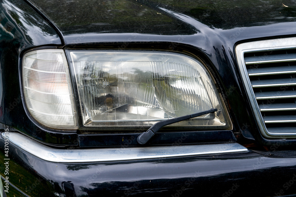 Closeup of headlights with windshield wipers of old cars