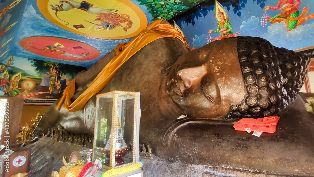 Fototapeta premium Huge stone statue of reclining buddha. Buddhist drawings and religious offerings. Phnom kulen national park. Siem Reap Province. Cambodia. South-East Asia