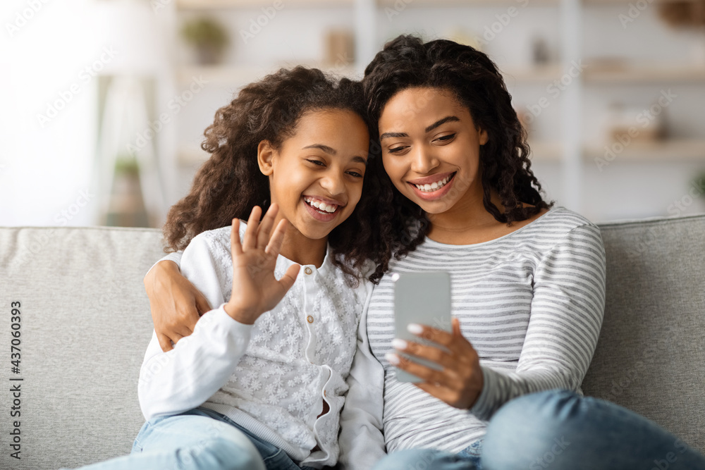 Cheerful black mother and daughter having video call via smartphone Cheerful black mother and daughter having video call via smartphone