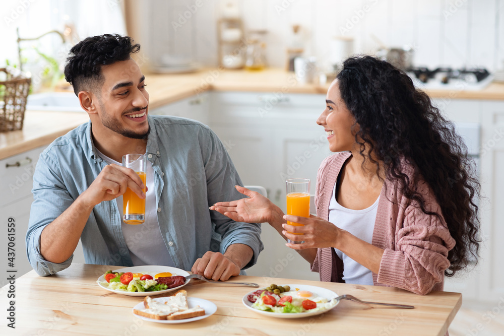 Cheerful young arab couple having breakfast together at home