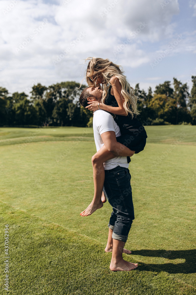 A guy and a girl are walking on a green meadow. Love story. Young couple in nature on a warm summer day. A guy and a girl are walking on a green meadow. Love story. Young couple in nature on a warm summer day.