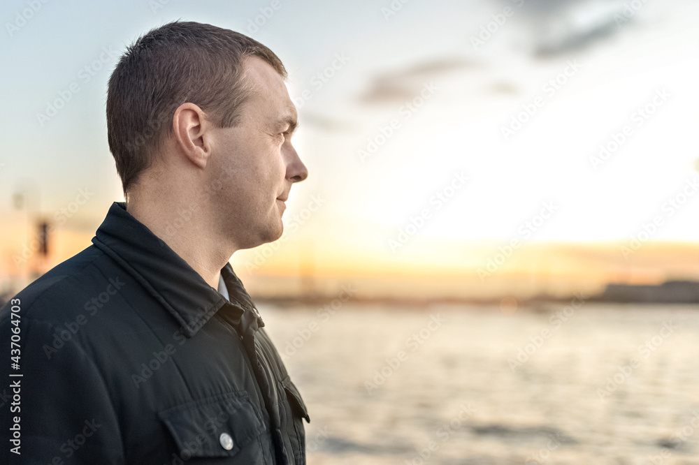 Portrait of a young man watching the sunset on the embankment of the river in the city Portrait of a young man watching the sunset on the embankment of the river in the city