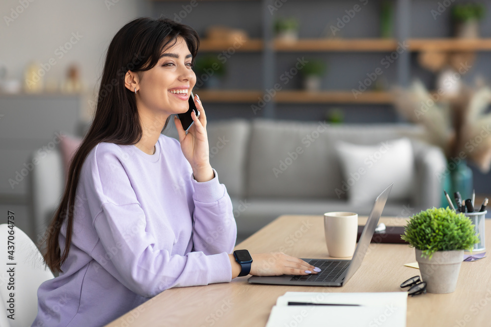 Smiling lady working and talking on phone at home Smiling lady working and talking on phone at home