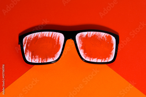 Summer concept of rest and fun. Sunglasses decorated with red paper. Isolated in orange and red. 