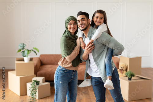 Tablou pe pânză Happy muslim family looking at camera, posing on moving day