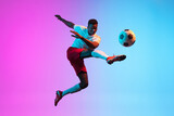 One African man, professional soccer football player training isolated on gradient blue pink background in neon light.
