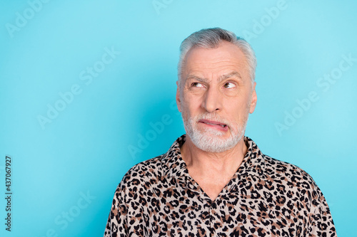 Photo of unhappy sad upset old man worry look empty space bite lip teeth isolated on pastel blue color background