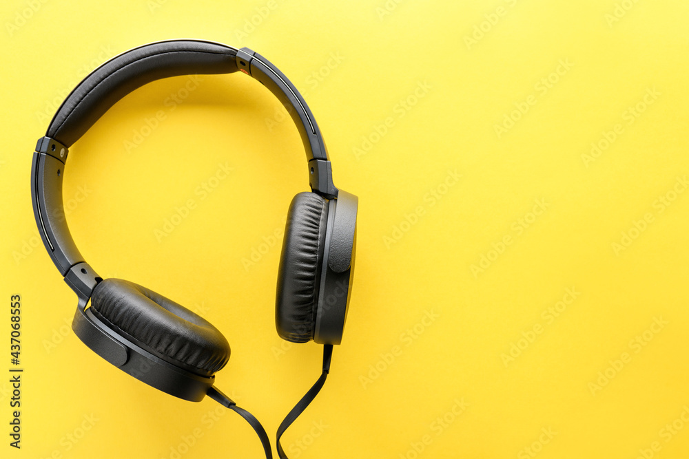Black wired Headphones on yellow background. Entertainment concept Black wired Headphones on yellow background. Entertainment concept