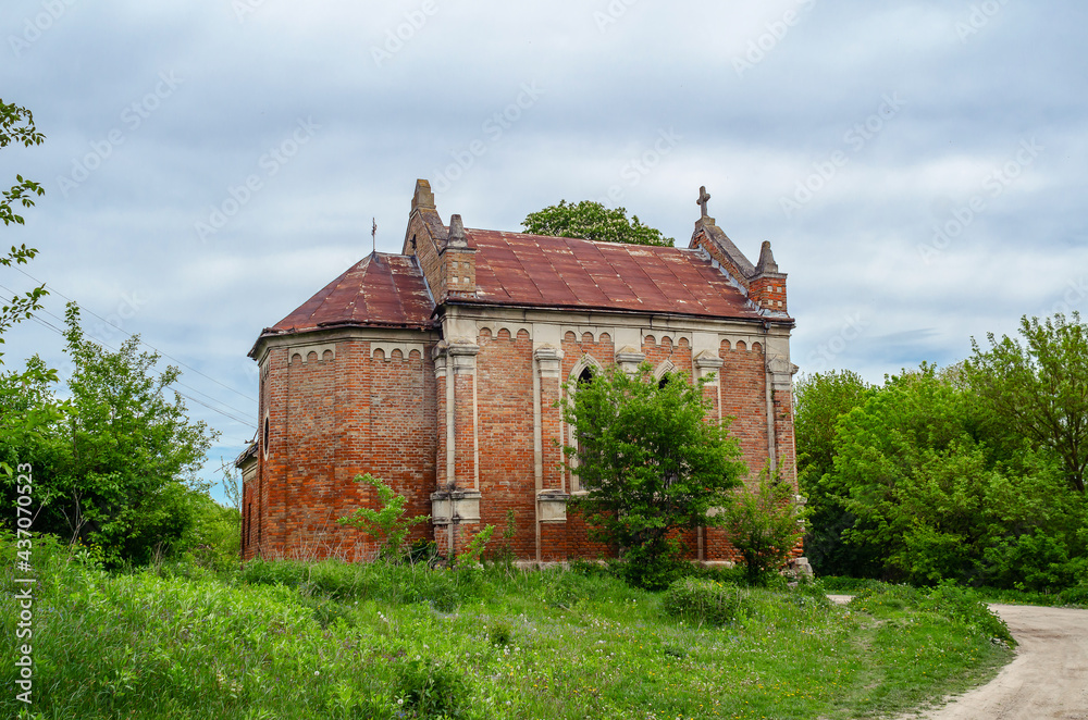Fototapeta premium Old abandoned church with red bricks on a background of trees