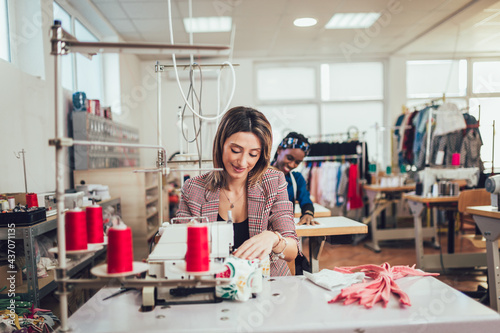 Young fashion designer using sewing machine in her workshop