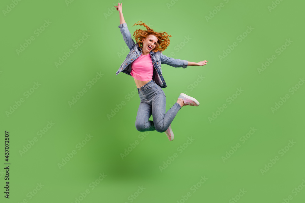 Full length photo of sweet charming young woman wear jeans outfit spectacles jumping high smiling isolated green color background Full length photo of sweet charming young woman wear jeans outfit spectacles jumping high smiling isolated green color background
