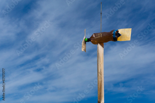A homemade weathervane pointer to the wind direction made with his hands from an empty plastic bottle, a propeller made of wood