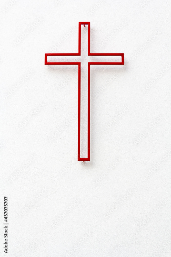 Red religious cross on white wall with copy space