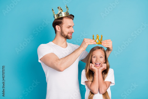Photo of handsome guy put crown on head amazed cheerful girl hands on cheeks isolated on blue color background
