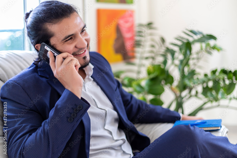 Young latino businessman talking in a phone call in home office Young latino businessman talking in a phone call in home office