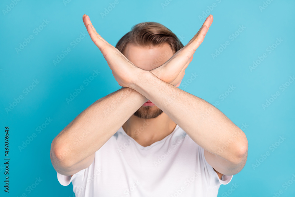 Photo of young person hands crossed covering face show stop enough symbol isolated on blue color background Photo of young person hands crossed covering face show stop enough symbol isolated on blue color background