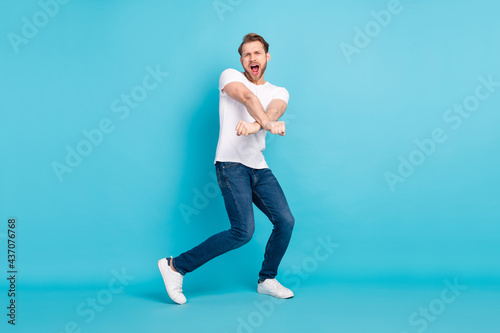 Full length photo of satisfied young man open mouth shout partying isolated on blue color background