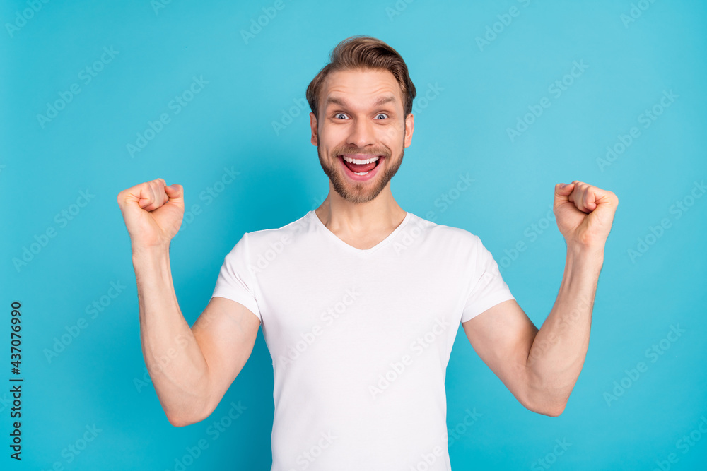 Portrait of astonished positive man fists up open mouth shout yes isolated on blue color background Portrait of astonished positive man fists up open mouth shout yes isolated on blue color background
