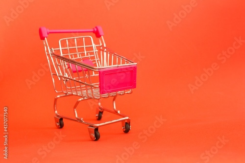 Mini shopping cart or trolley isolated on red background with copy space.