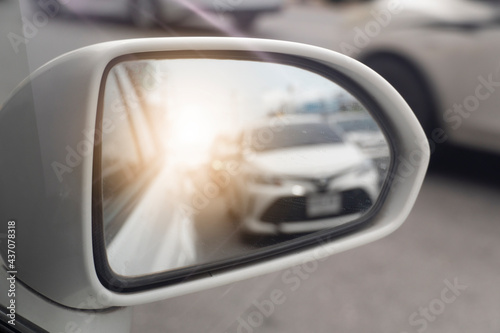 Fototapeta Naklejka Na Ścianę i Meble -  View of traffic from behind through the mirrors wing of a white car. with abstract of shining from behind.