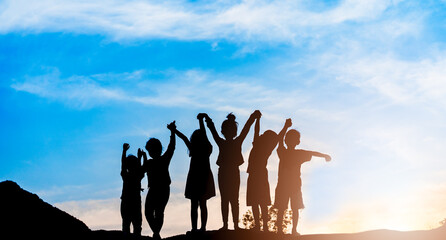 Silhouette back view refugee kid group playing in sunset.Kid child boy and girl worship.Raised hands blessing praying worship, Hope, freedom, Diverse, Faith, Praise, world refugee day.Adoption kid.