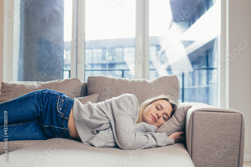 Young woman sleep resting at home on couch after a hard day's work. Relax calm and rest. On a soft cozy comfortable sofa. Comfort safety. Female with closed eyes feels comfortable and safe in warmth  © Liubomir