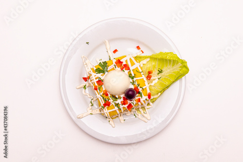 Top view image of a portion of Peruvian causa limeña  garnished with mayonnaise, boiled egg, peppers and lettuce